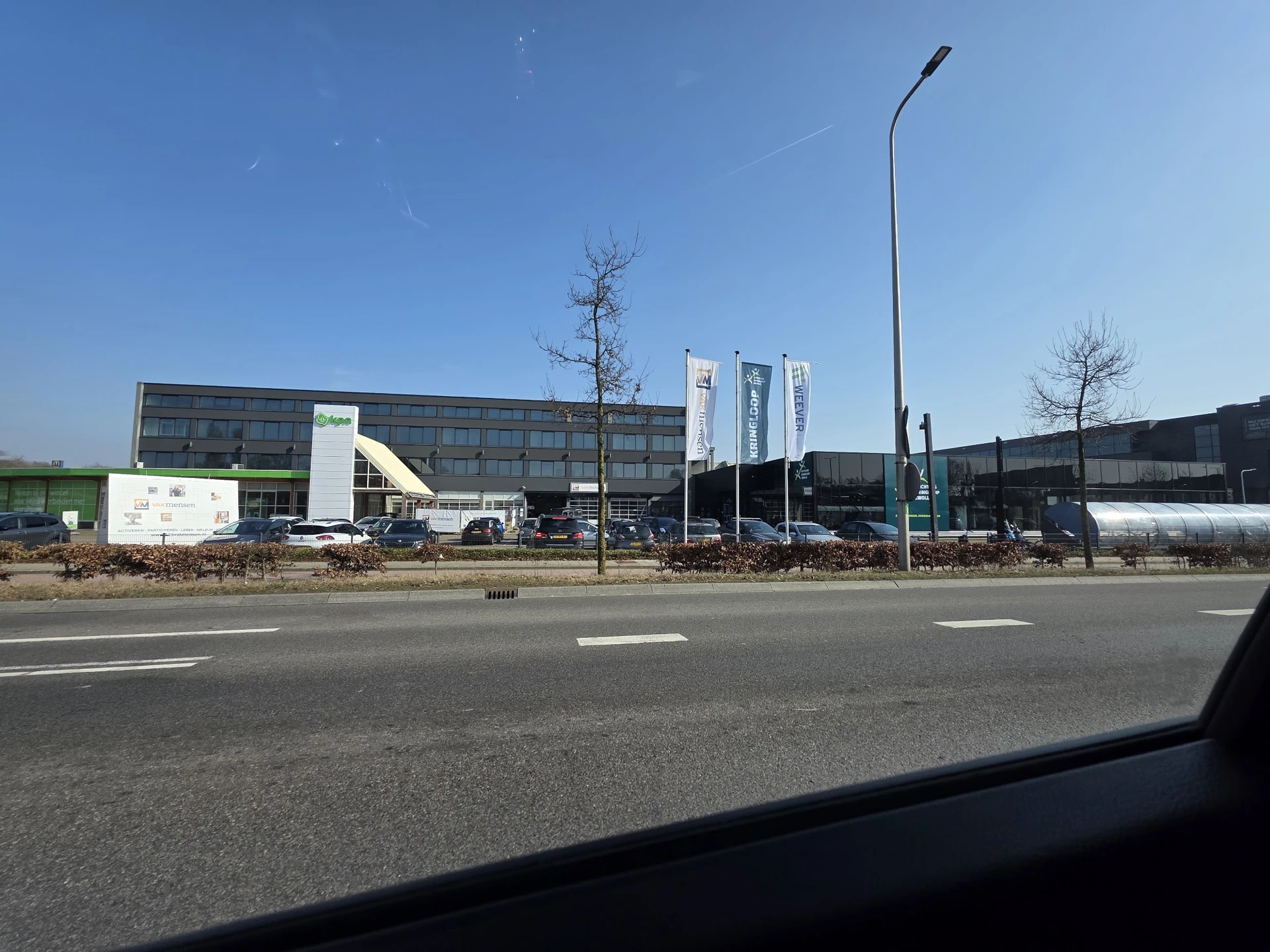 Voorgevel van kringloopwinkel met parkeerplaats en moderne grijze gevel langs straat