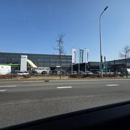 Voorgevel van kringloopwinkel met parkeerplaats en moderne grijze gevel langs straat