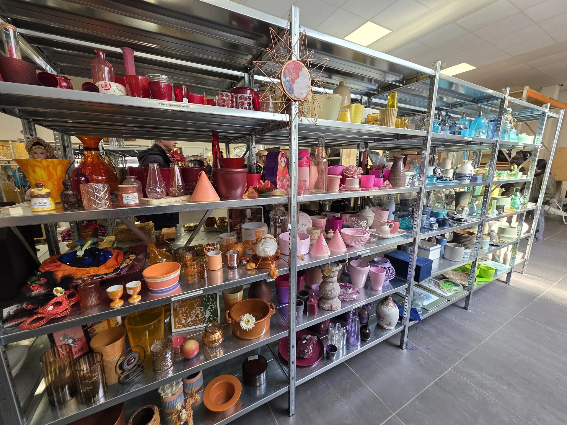 Metalen stellingen vol met roze en rode kaarsen, kaarshouders en decoratieve items