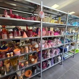 Metalen stellingen vol met roze en rode kaarsen, kaarshouders en decoratieve items