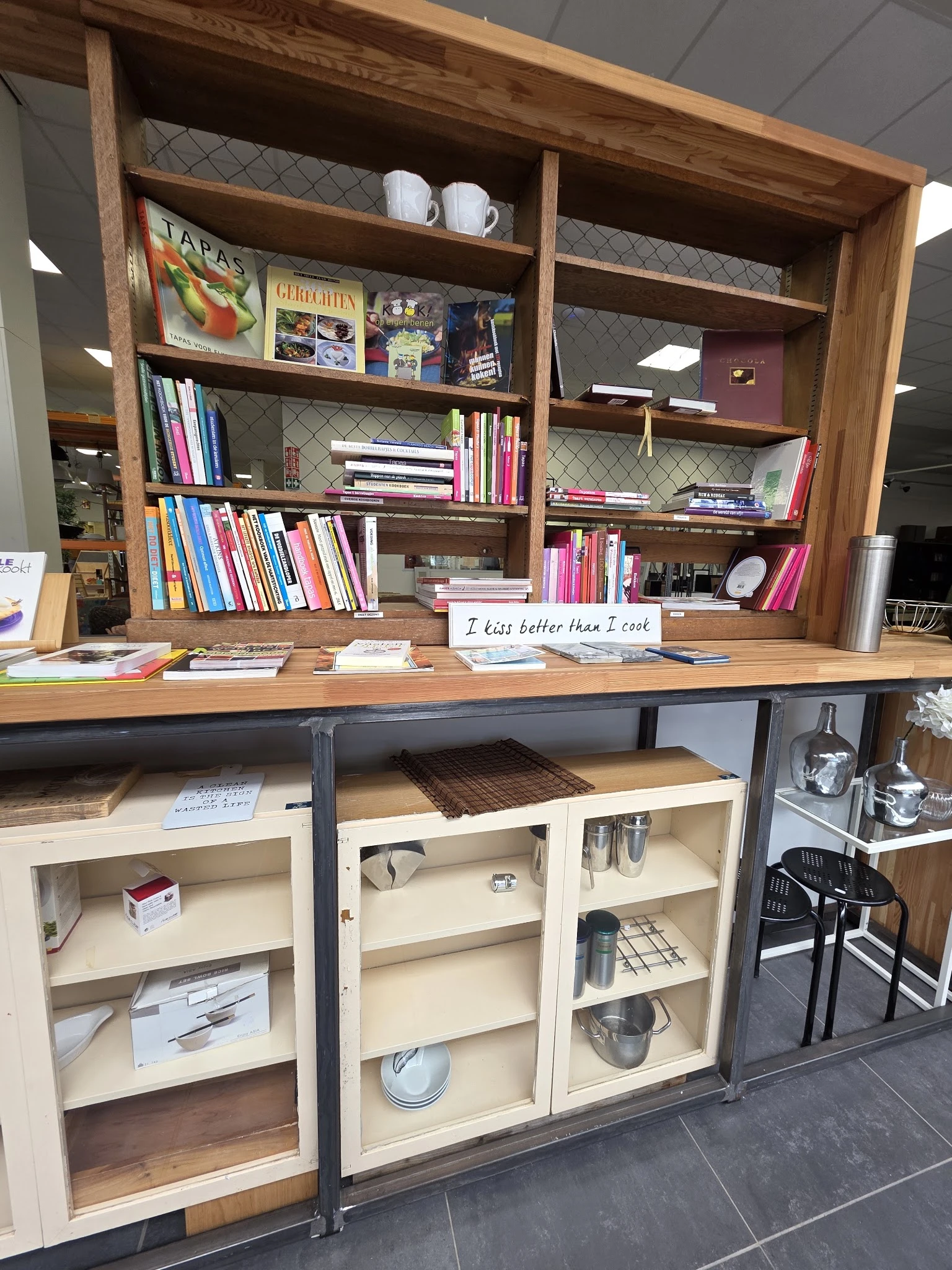 Houten boekenkasten en werktafel met boeken en huishoudartikelen in een kringloopwinkel