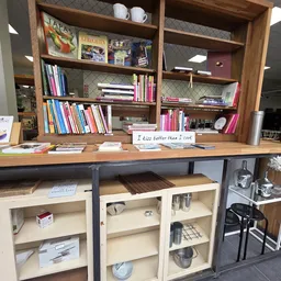 Houten boekenkasten en werktafel met boeken en huishoudartikelen in een kringloopwinkel