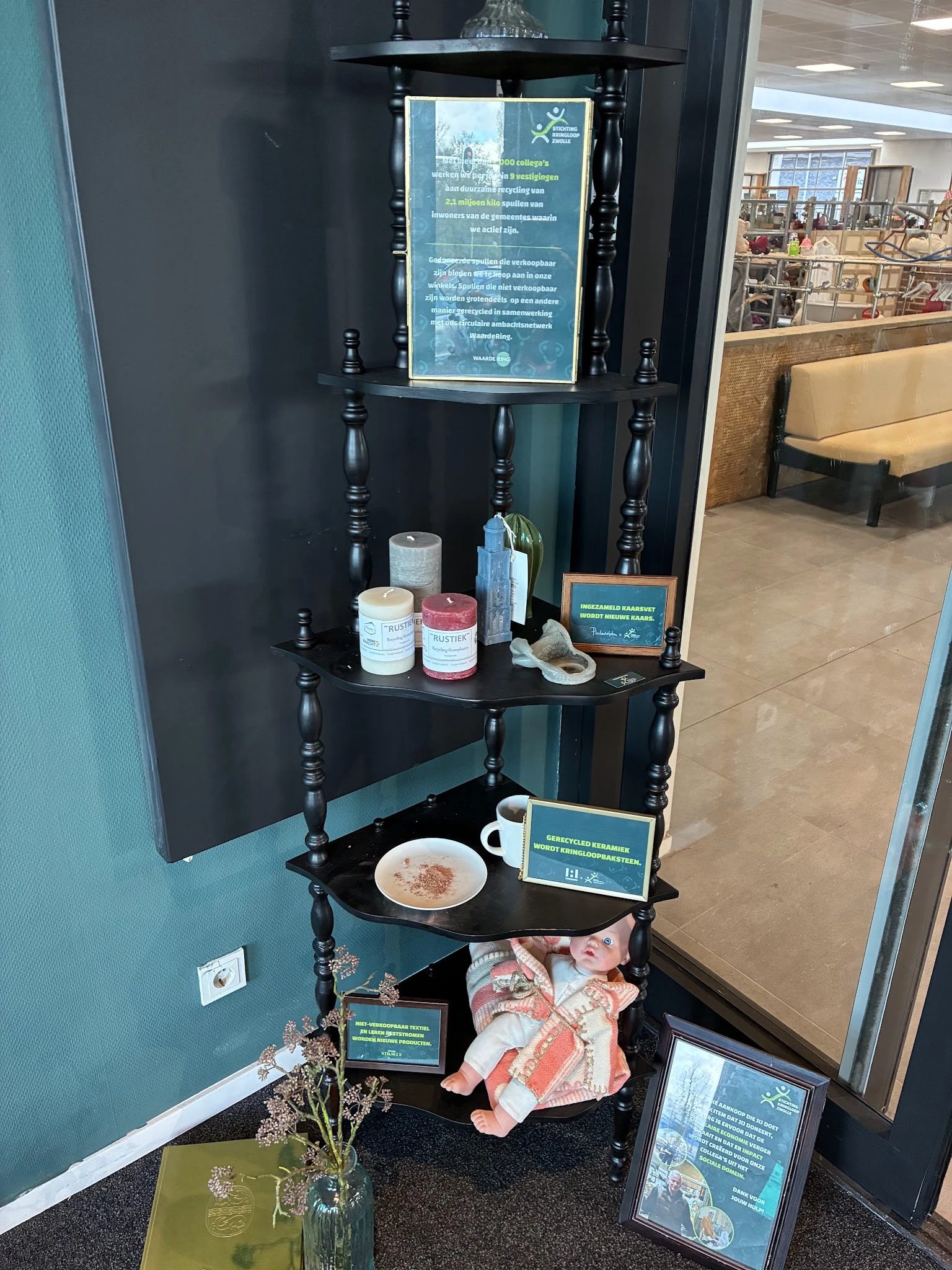 Zwarte etagère met decoratieve items, kaarsen, glazen flessen en een bord met eten