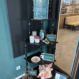 Zwarte etagère met decoratieve items, kaarsen, glazen flessen en een bord met eten