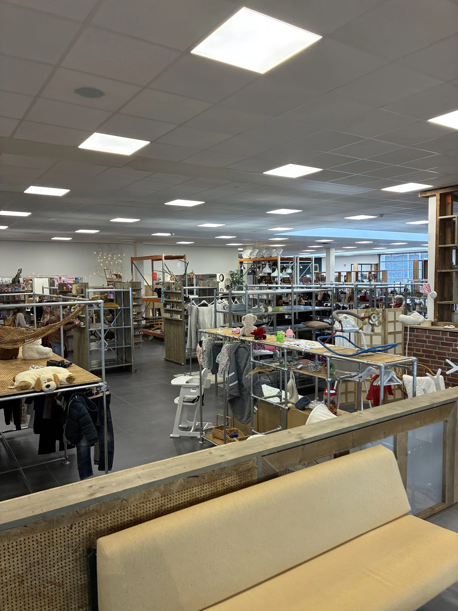 Winkelvloer van kringloopwinkel met stellingen, tafels, boeken en huishoudspullen