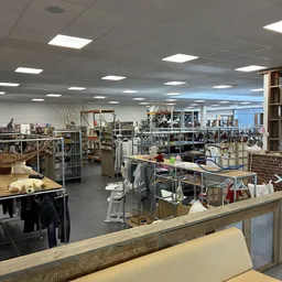 Winkelvloer van kringloopwinkel met stellingen, tafels, boeken en huishoudspullen