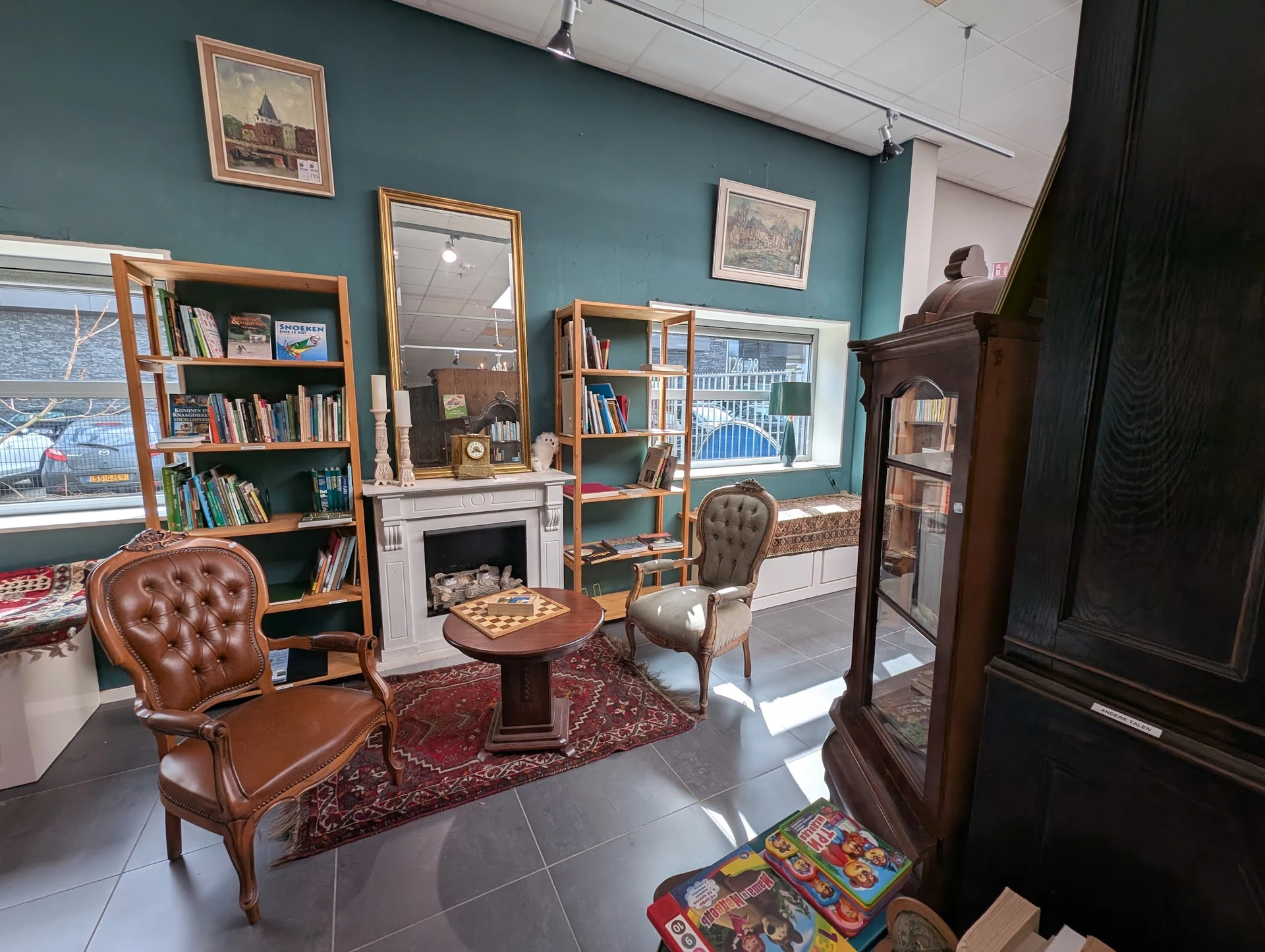 Vintage ingerichte woonkamer met leren fauteuils, boekenkasten, spiegel en open haard in kringloopwinkel