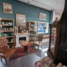 Vintage ingerichte woonkamer met leren fauteuils, boekenkasten, spiegel en open haard in kringloopwinkel