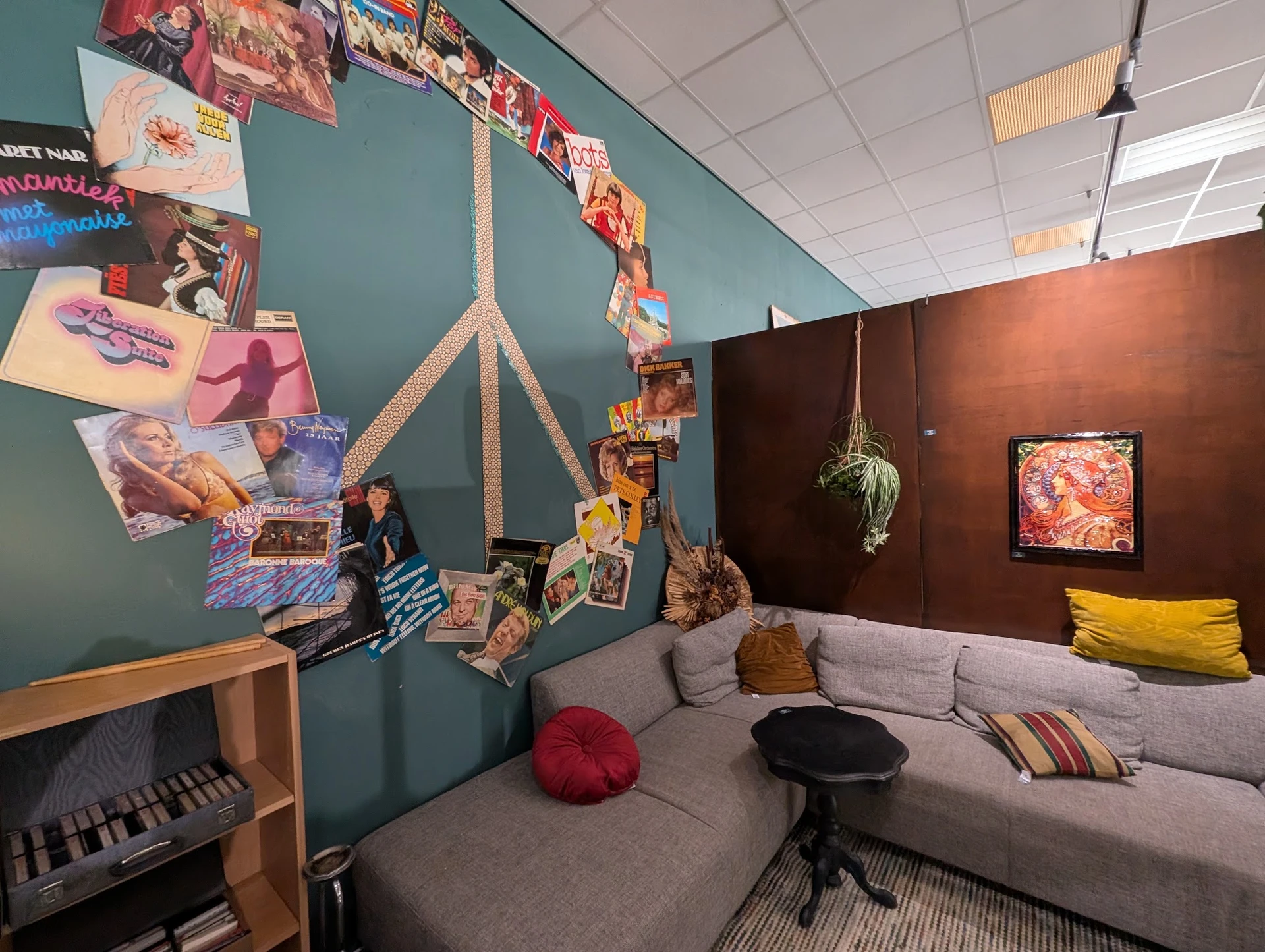 Ingerichte zithoek met grijze bank, kleurrijke kussens en decoraties aan turquoise en bruine wanden