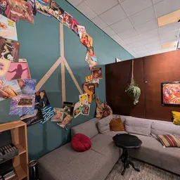 Ingerichte zithoek met grijze bank, kleurrijke kussens en decoraties aan turquoise en bruine wanden