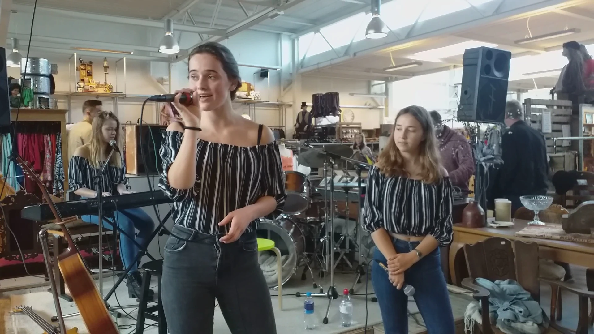 Vrouwen aan het zingen met microfoon in een werkplaats met muziekapparatuur