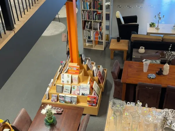 Bovenaanzicht van kringloopwinkel met boekenrek, houten meubels, boekenstandaard en diverse decoratieve items