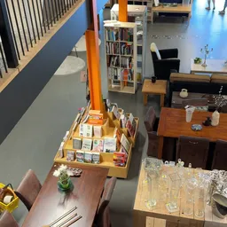 Bovenaanzicht van kringloopwinkel met boekenrek, houten meubels, boekenstandaard en diverse decoratieve items