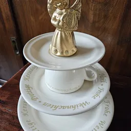 Wit porseleinen servieswerk met gouden engelfiguur als deksel, gestapeld in drie lagen