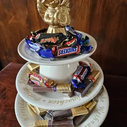 Decoratieve schaal met chocoladerepen en snoepjes, met gouden decoratie bovenop