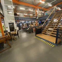 Winkelvloer met houten trap, stellingen, meubilair en gele veiligheidsmarkeringen