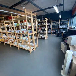 Winkelvloer met houten stellingen vol spullen, donkerblauwe muren en verschillende kasten met tweedehands artikelen