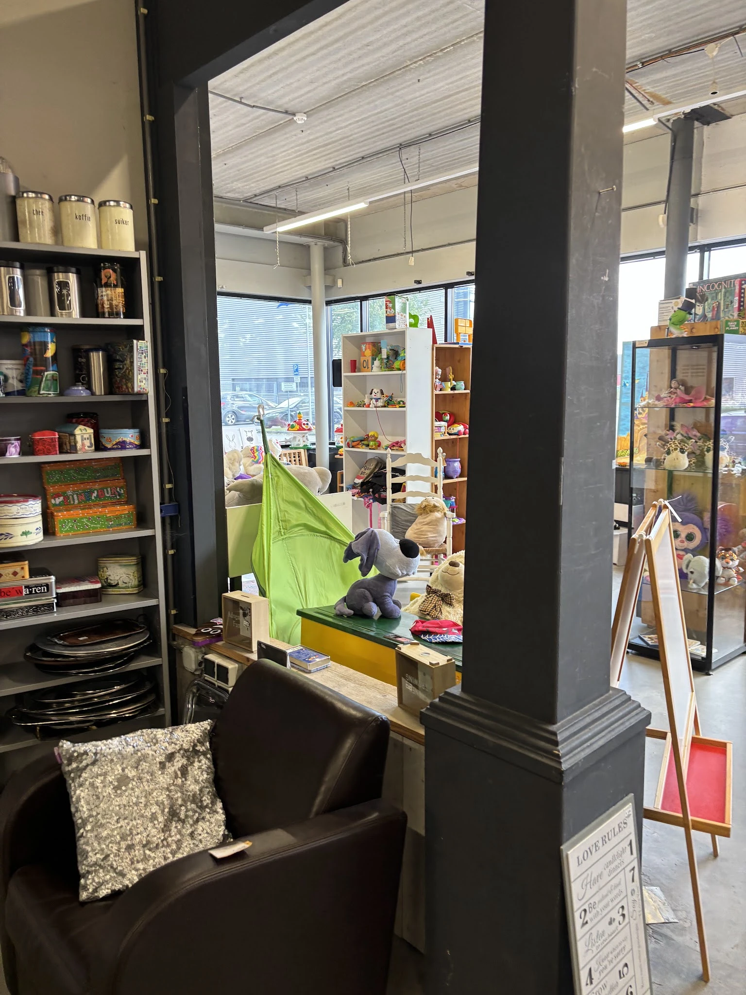 Winkelinterieur met boekenkasten, speelgoed en verschillende rekken met tweedehands spullen