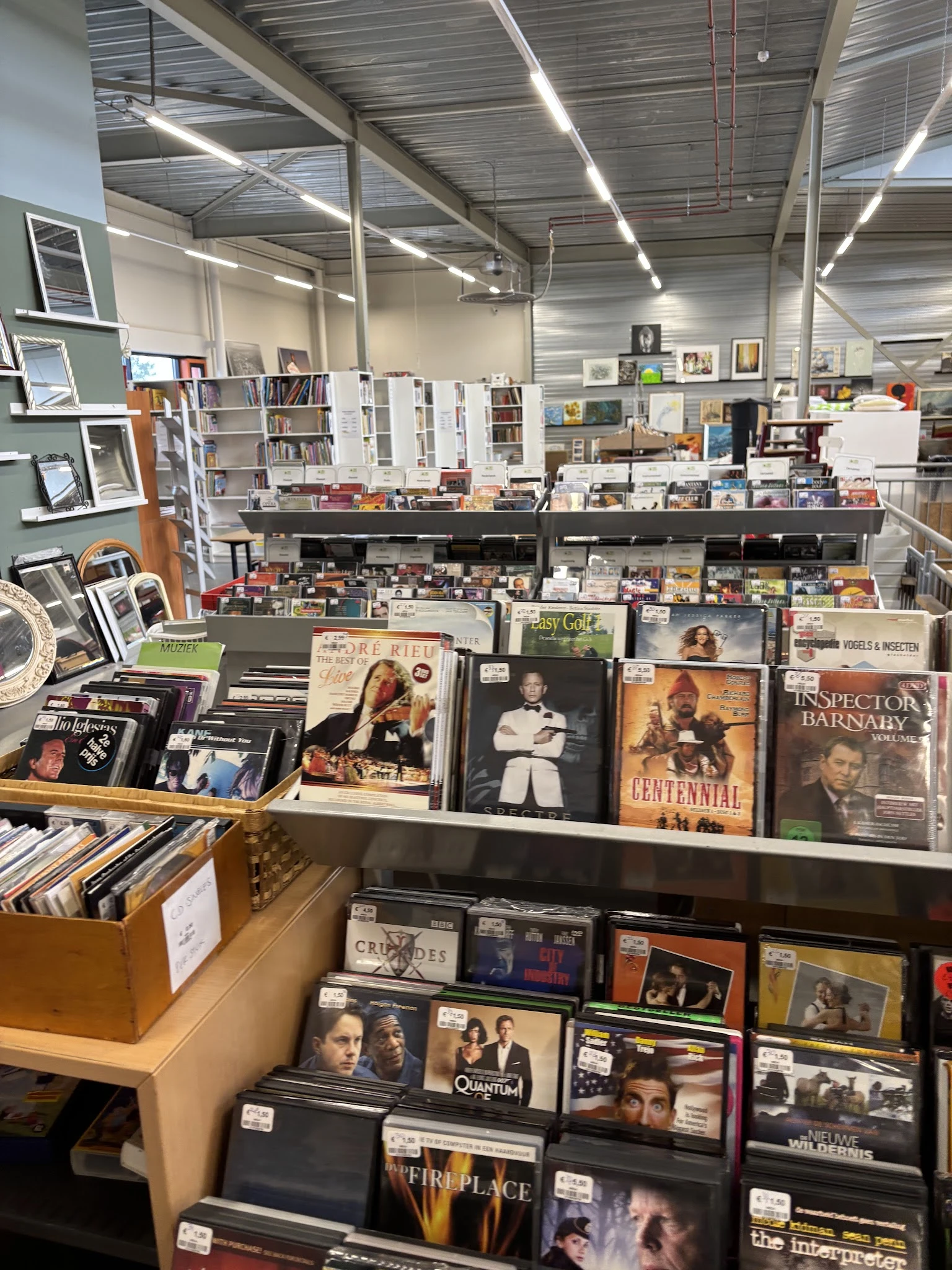Uitgestalde cd's, dvd's en boeken op planken en toonbanken in de kringloopwinkel