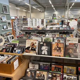 Uitgestalde cd's, dvd's en boeken op planken en toonbanken in de kringloopwinkel