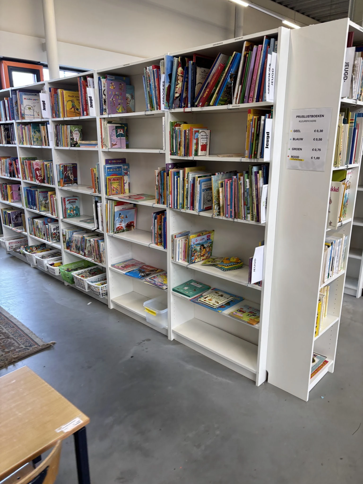 Witte boekenkast met verschillende genres boeken, dvd's en media netjes uitgestald op meerdere niveaus