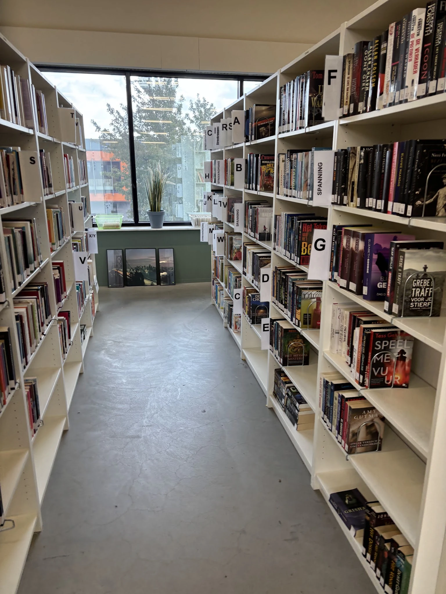 Gang tussen boekenrekken in een tweedehands boekwinkel met alfabetische ordening
