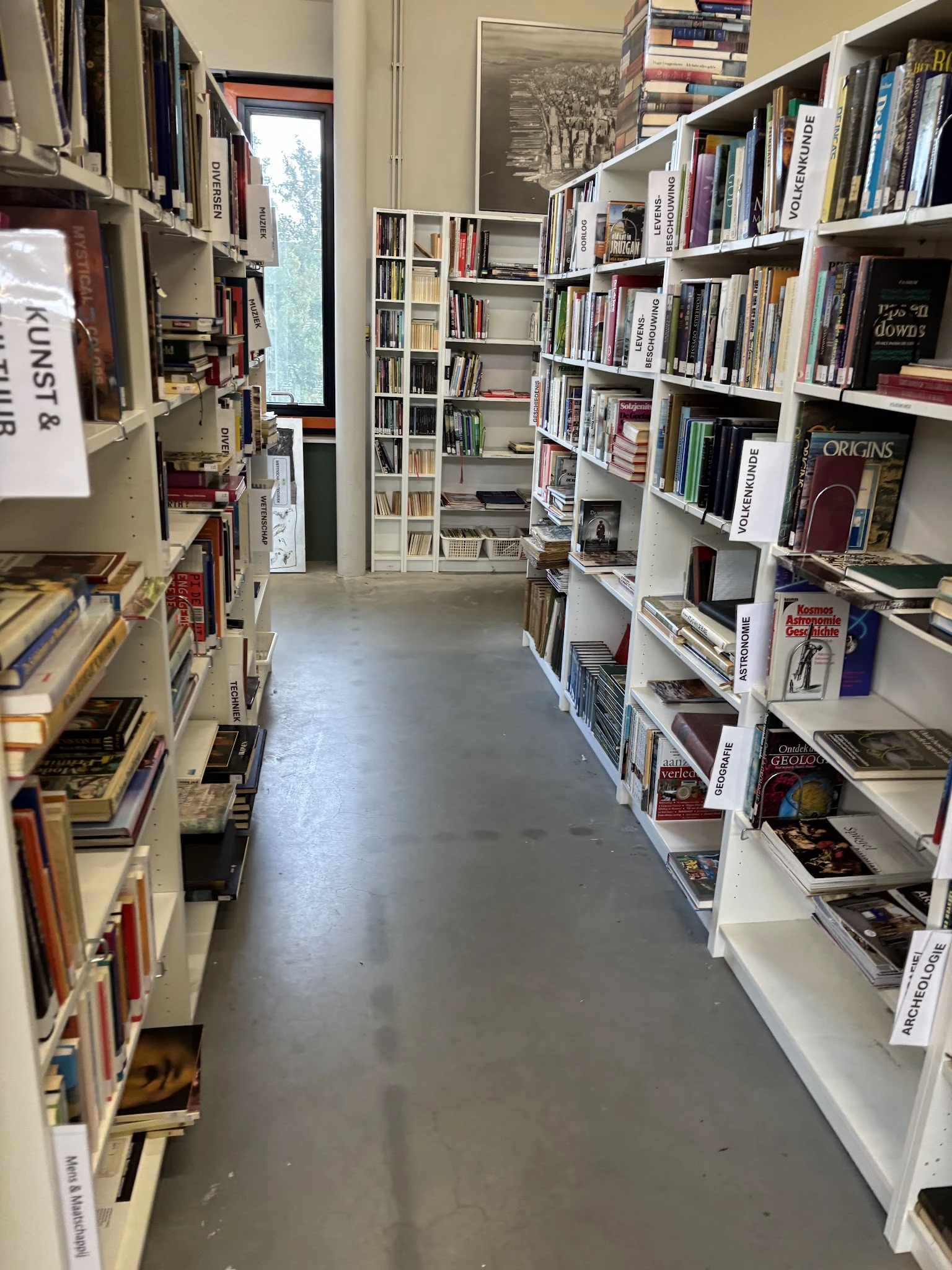 Gangpad met boekenrekken aan beide zijden in een kringloopwinkel