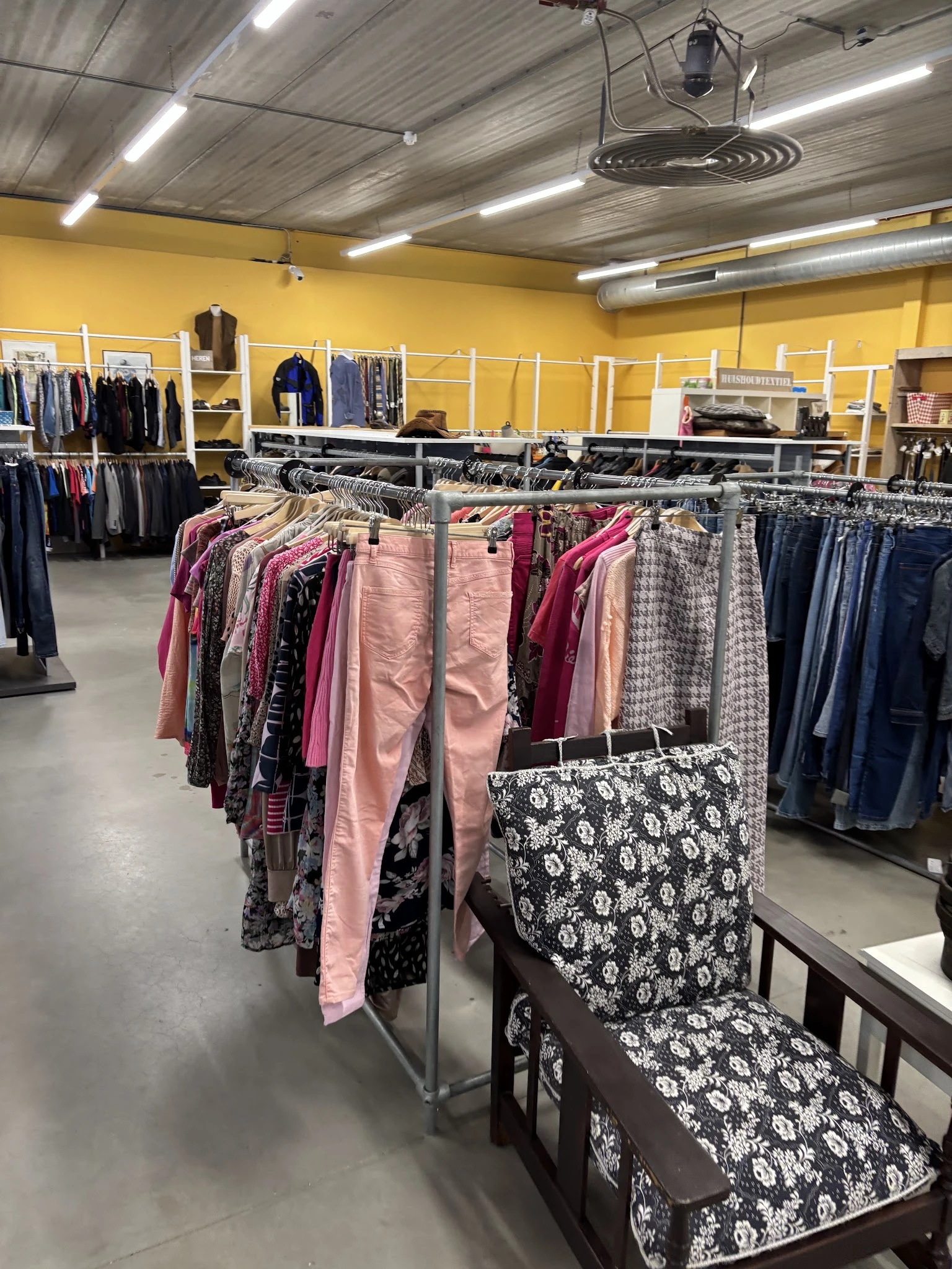 Rekken met tweedehands dameskleding in verschillende kleuren en patronen