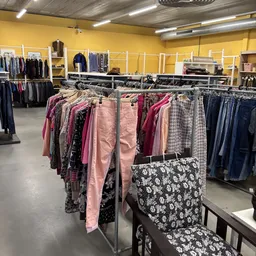 Rekken met tweedehands dameskleding in verschillende kleuren en patronen