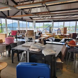Ruime winkelruimte met diverse tweedehands meubels, stoelen, tafels en huishoudartikelen, grote ramen met uitzicht
