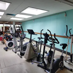Fitnessapparaten zoals hometrainers en crosstrainers in een kringloopwinkel met turquoise wand