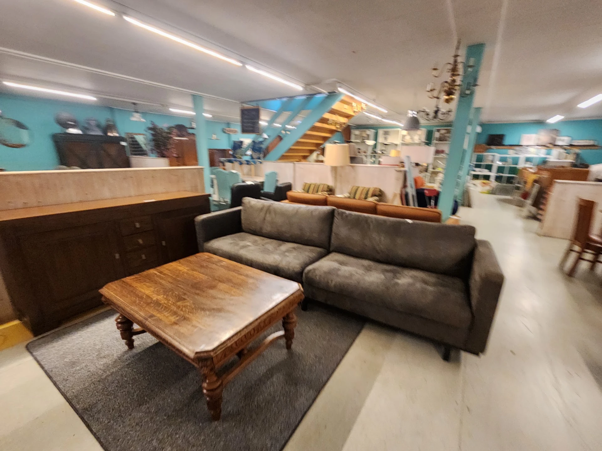 Winkelvloer met grijze sofa, houten salontafel op vloerkleed en houten kast, turquoise wanden