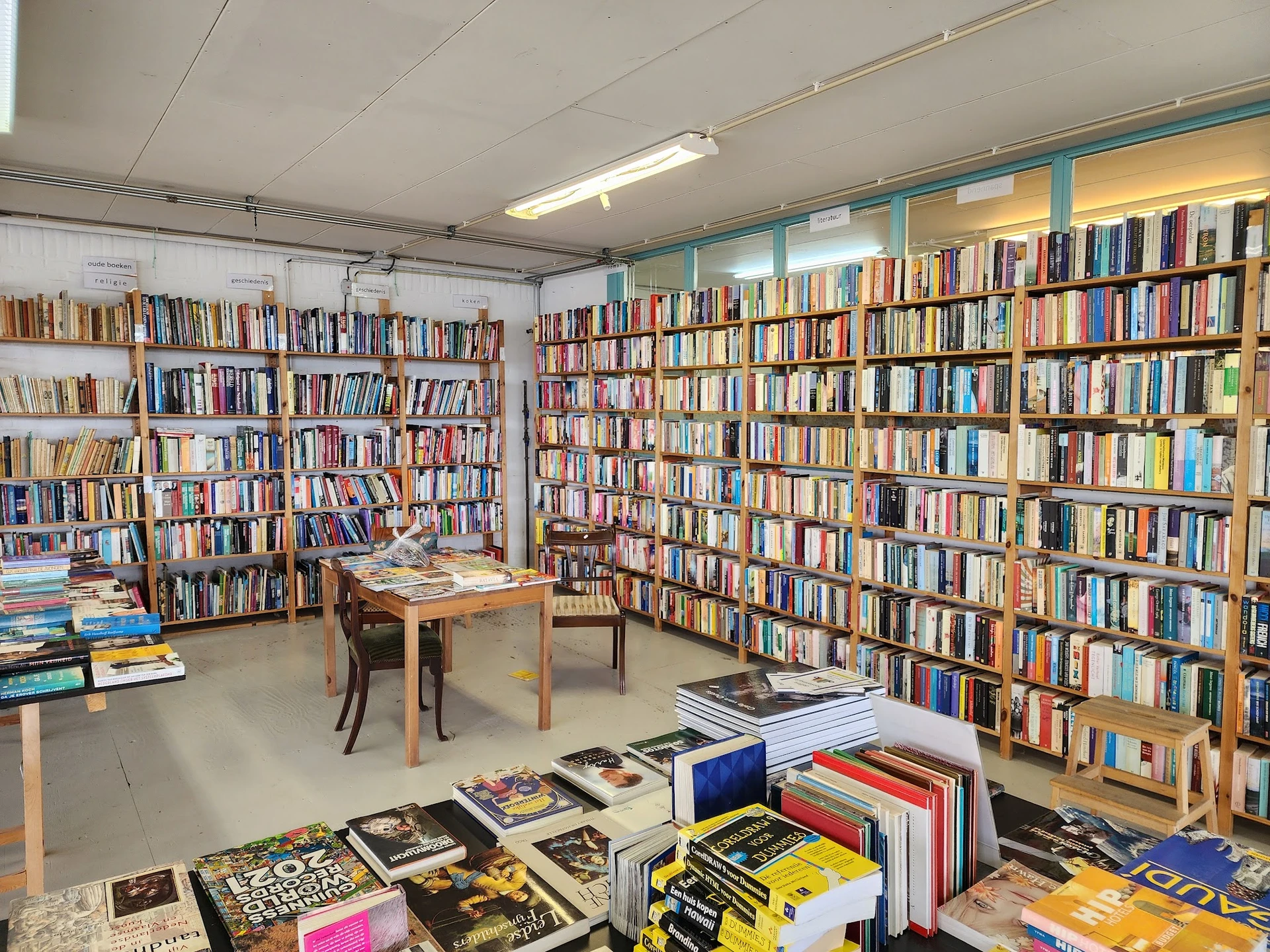 Boekenwinkelinterieur met uitgebreide boekenkasten langs de wanden en losse boeken op de grond