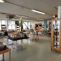 Ruim winkelinterieur met boekenkasten, zitmeubels en displayrekken met tweedehands spullen