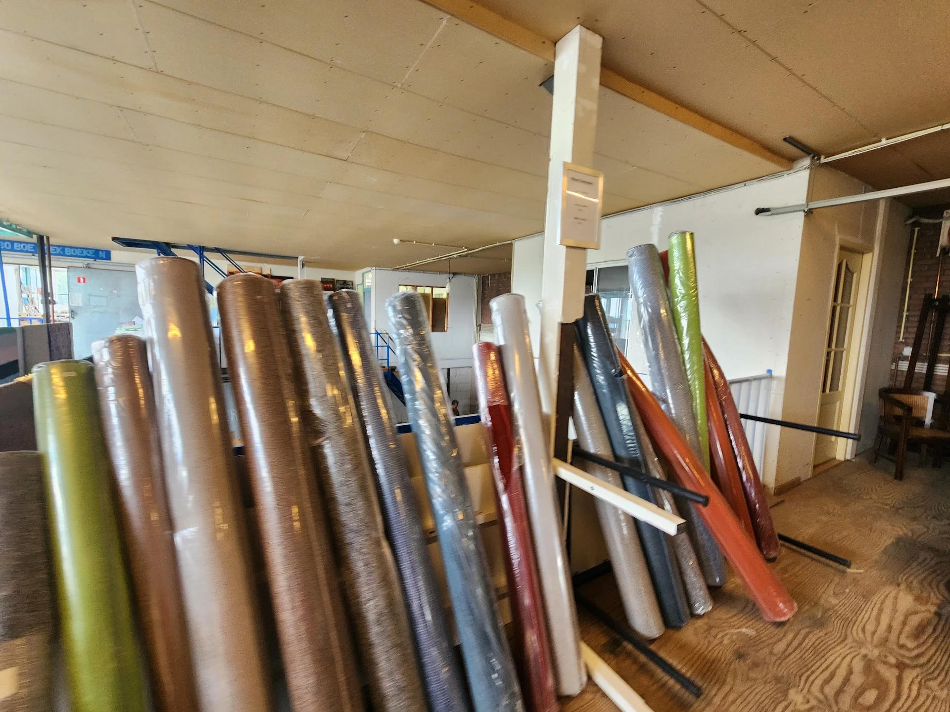 Uitgestalde rollen behang en vloerbedekking in verschillende kleuren en patronen