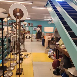 Winkelinterieur met turquoise muren, gele vloer, muziekinstrumenten, meubels en een roltrap