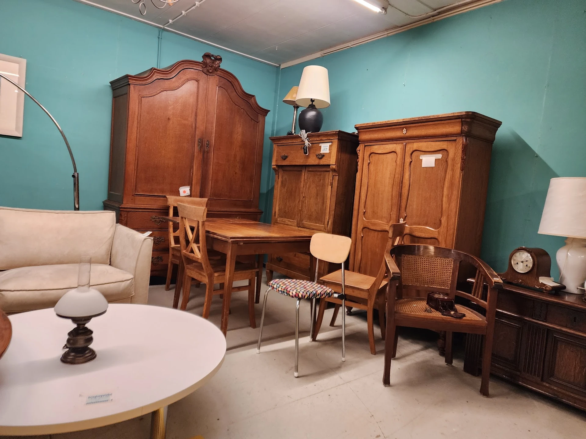 Ingerichte kamer met houten meubelen, turquoise wanden en vintage interieurstukken in een kringloopwinkel