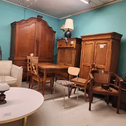Ingerichte kamer met houten meubelen, turquoise wanden en vintage interieurstukken in een kringloopwinkel