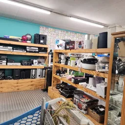 Winkelinterieur met houten stellingen vol elektronica, computers en apparaten, blauwe vloer en turquoise muur