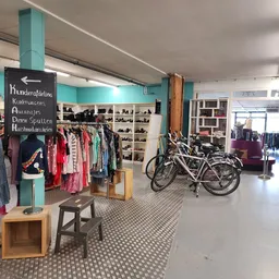 Winkelvloer met kledingrekken, fietsen, schoenenrek en houten meubels in een kringloopwinkel
