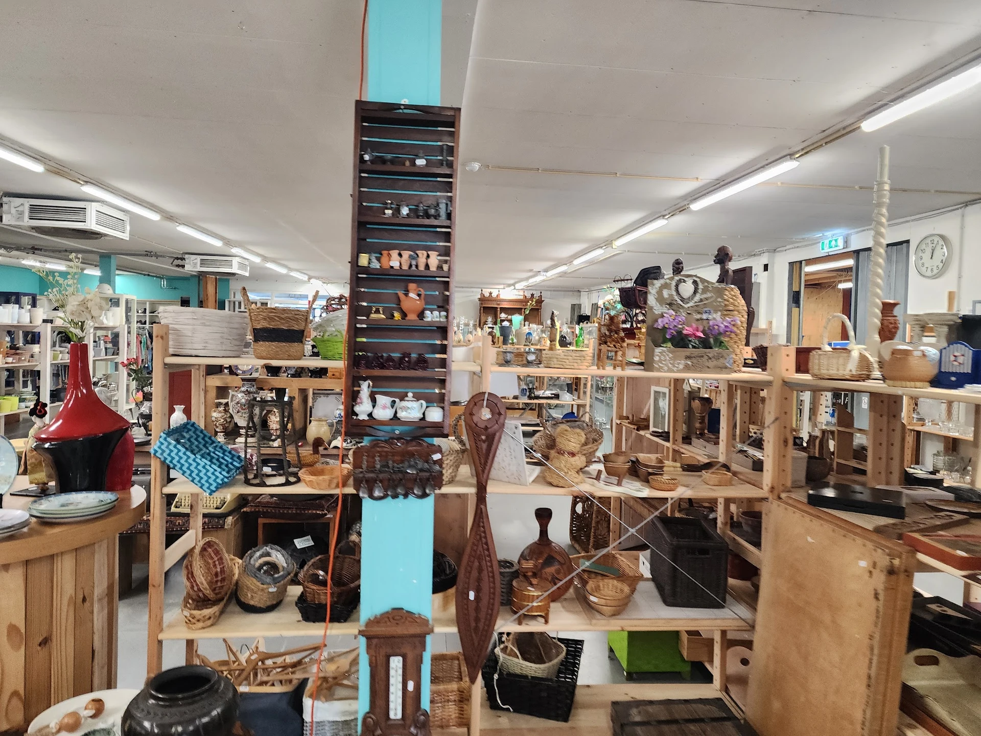 Winkelvloer met houten meubels, rekken met diverse spullen en decoratieve items in een kringloopwinkel