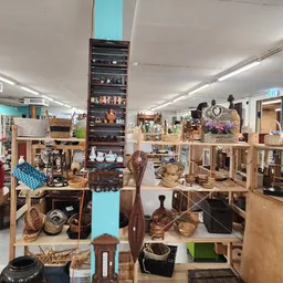 Winkelvloer met houten meubels, rekken met diverse spullen en decoratieve items in een kringloopwinkel
