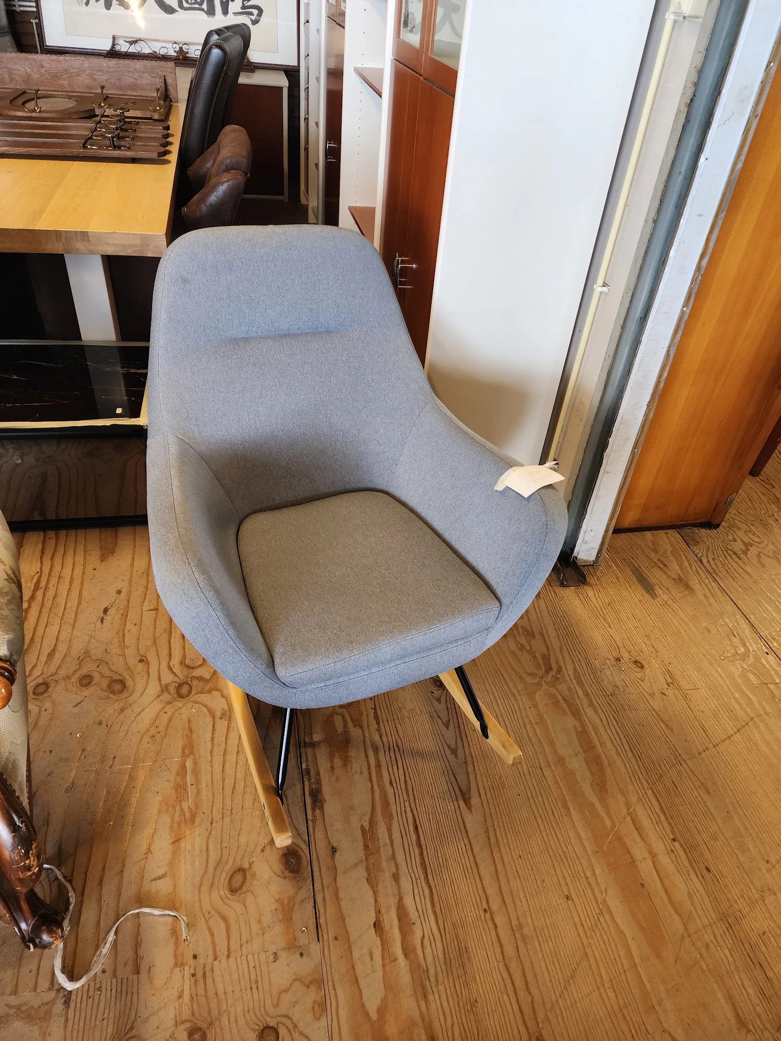 Grijsblauwe moderne fauteuil met grijze zitting en zwarte poten op houten vloer