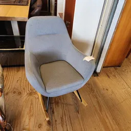 Grijsblauwe moderne fauteuil met grijze zitting en zwarte poten op houten vloer