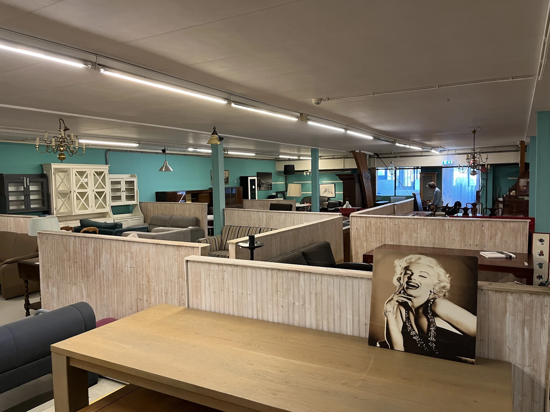 Winkelinterieur met houten scheidingswanden, toonbanken, turquoise muren en verlichte plafondlampen