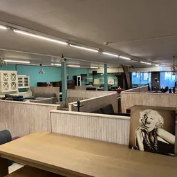 Winkelinterieur met houten scheidingswanden, toonbanken, turquoise muren en verlichte plafondlampen