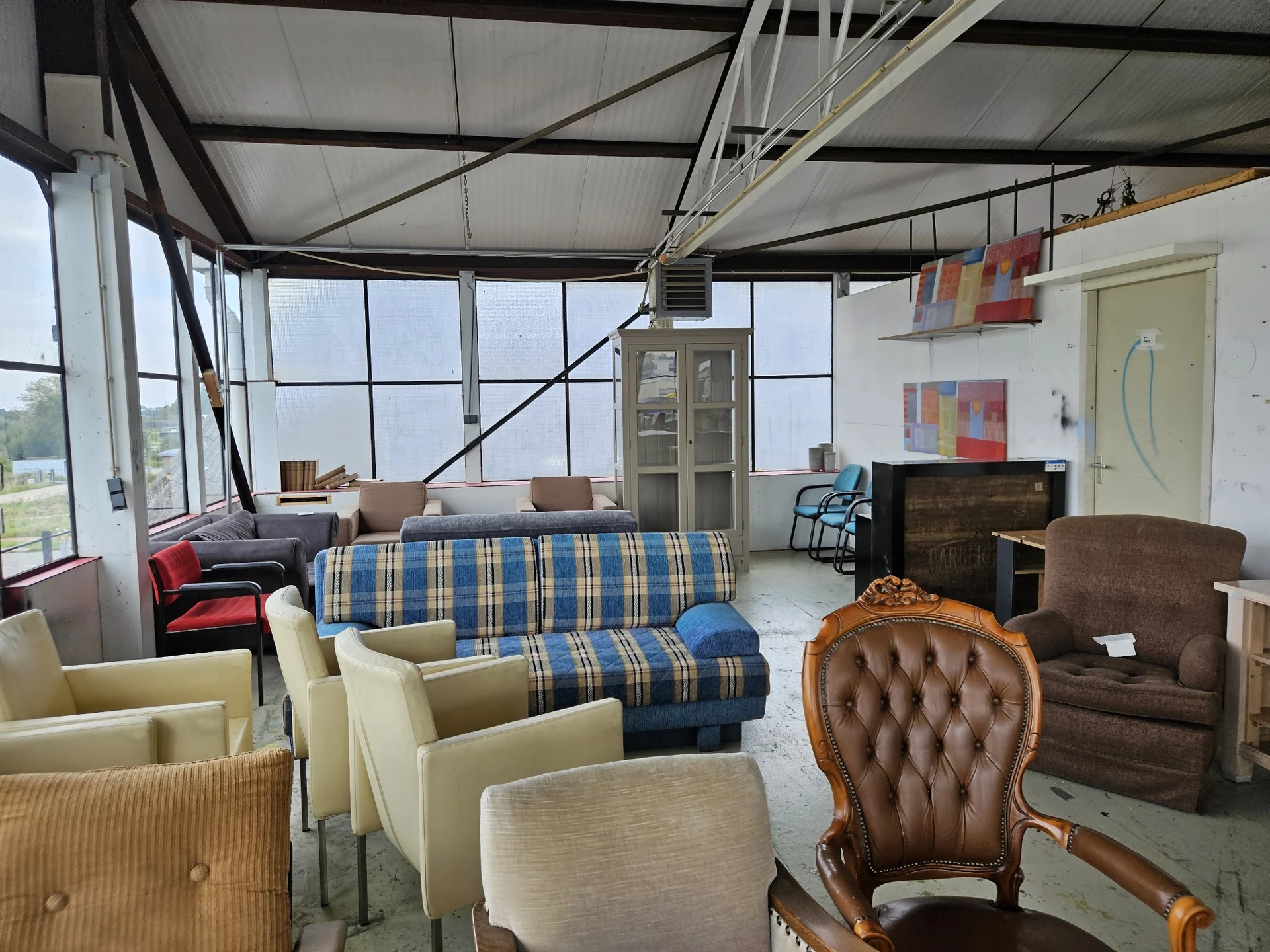 Grote winkelruimte met meubels waaronder banken, stoelen en fauteuils, grote ramen en dakramen aan de bovenkant