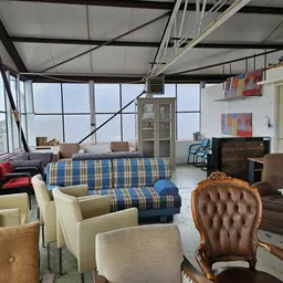 Grote winkelruimte met meubels waaronder banken, stoelen en fauteuils, grote ramen en dakramen aan de bovenkant