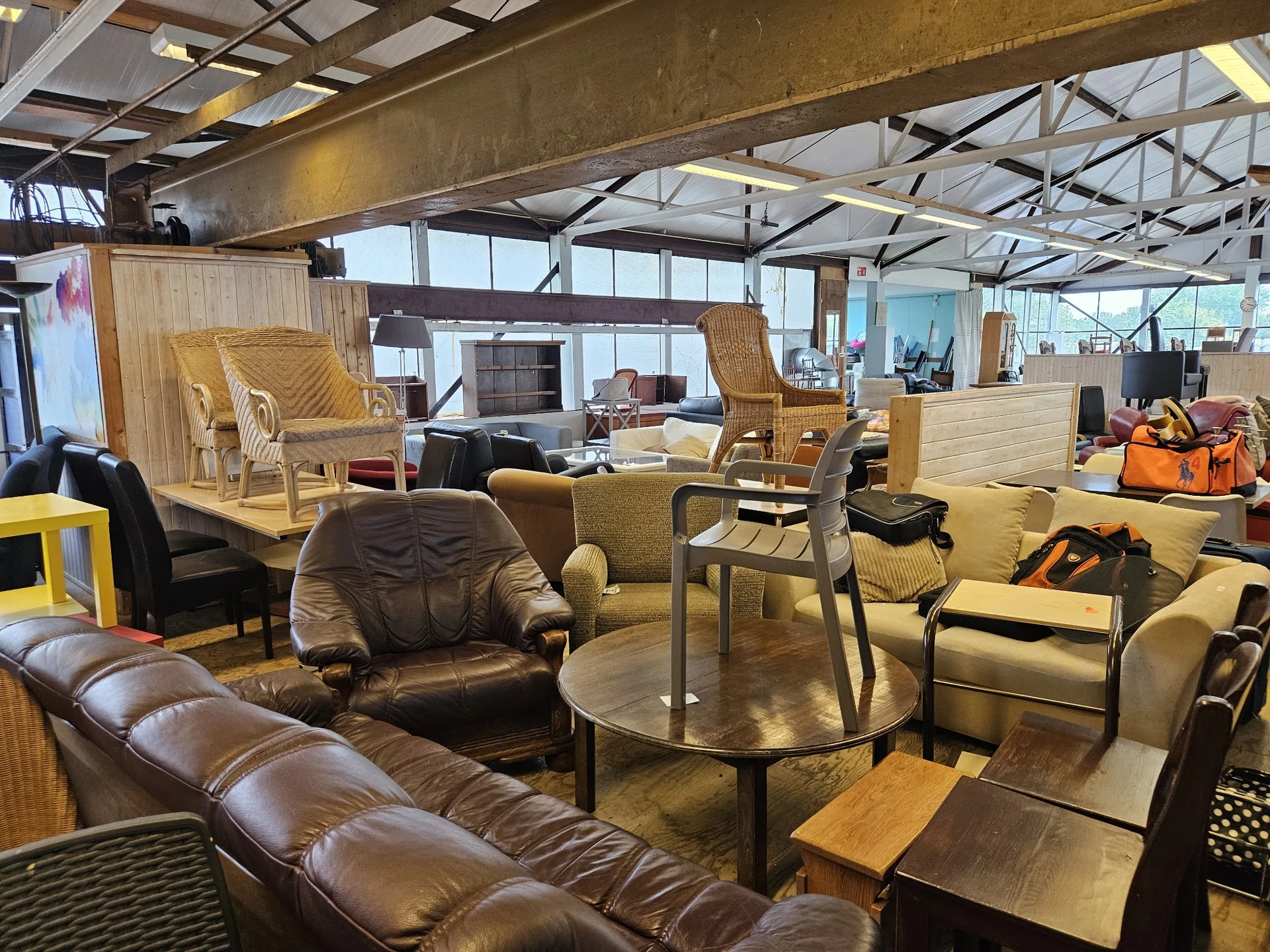 Winkelinterieur met meubels: leren bank, fauteuils, stoelen en tafels in bruine en beige tinten.