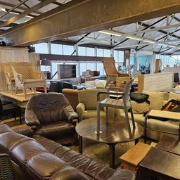 Winkelinterieur met meubels: leren bank, fauteuils, stoelen en tafels in bruine en beige tinten.